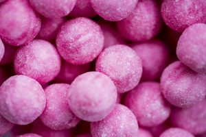 Full frame of round sweets made of bright pink candy covered in sugar and looking tempting